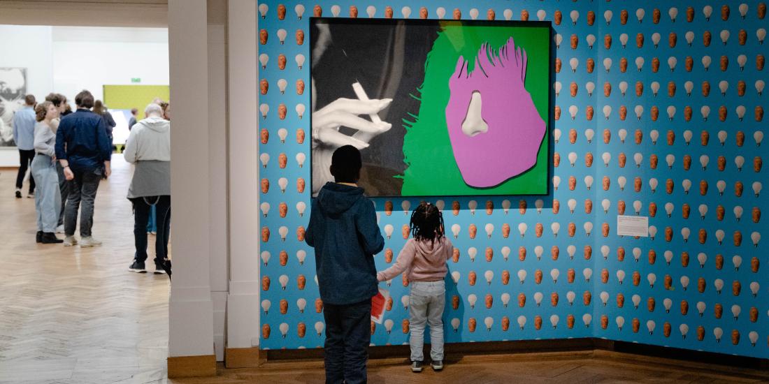 The image shows children admiring a work by John Baldessari at Bozar