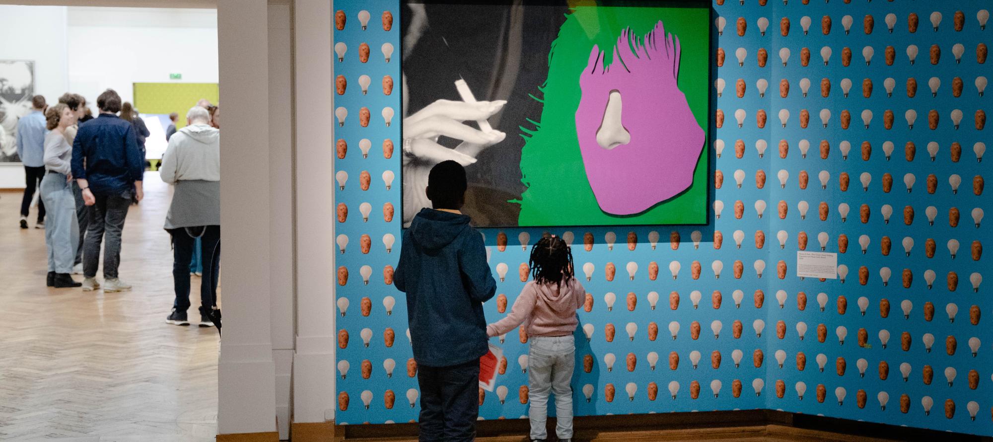 The image shows children admiring a work by John Baldessari at Bozar