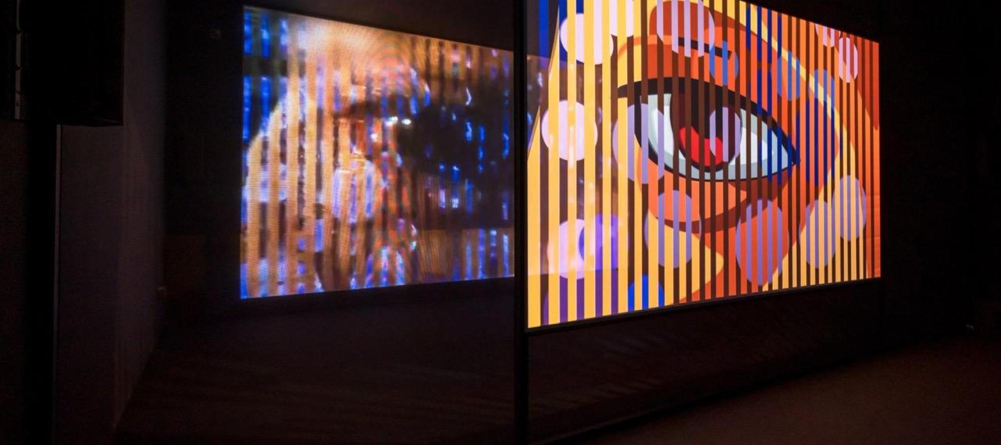 Ho Tzu Nyen, T for Time, 2023–ongoing, 2-channel synchronized HD videos (16:9, colour, and eight-channel sound, approximately 60 min), voile screen, scrim walls, real-time algorithmic editing and compositing system. Installation view at Singapore Art Museum, 2023.